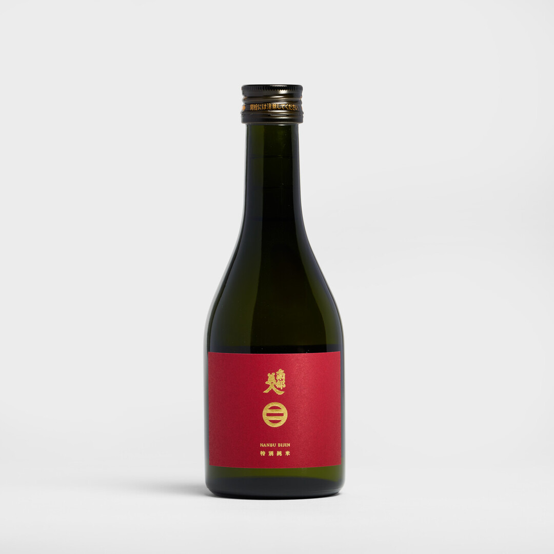 A small, dark bottle with a red label and gold words of Nanbubijin