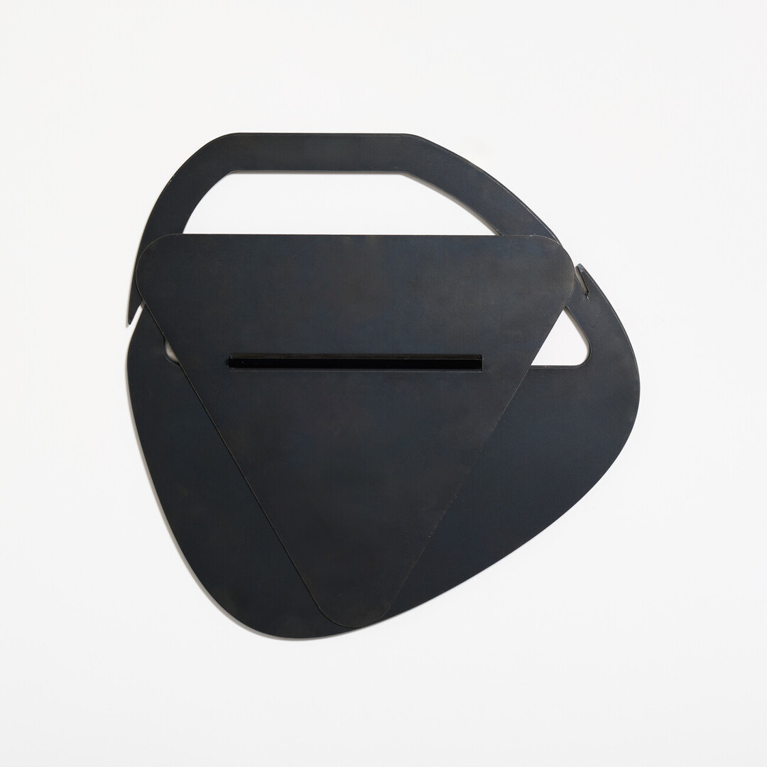 A black laser cut fire pit collapsed into a easy to hold manner produced by PLAY METAL FIRE PLACE