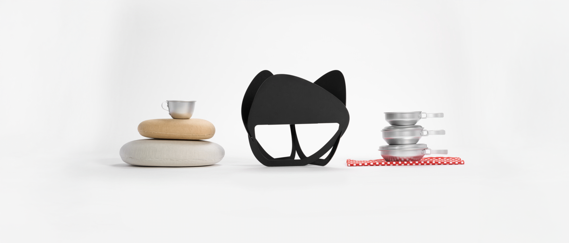 A collection of outdoor items such as a small aluminium cup on top of paper rock-shaped boxes, a laser-cut fire pit and collapsible five piece outdoor eating set.