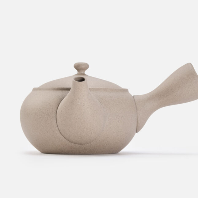 A beige rounded teapot for green tea with a handle on the side