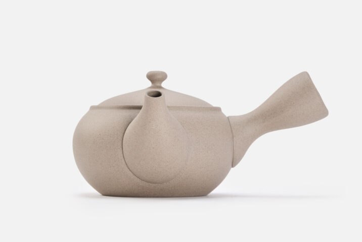 A beige rounded teapot for green tea with a handle on the side
