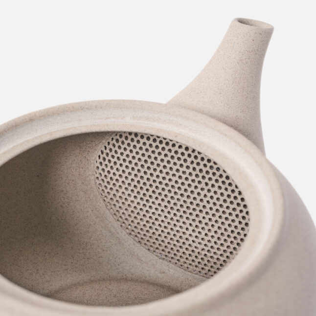 A built in filter inside the beige tea pot for green tea