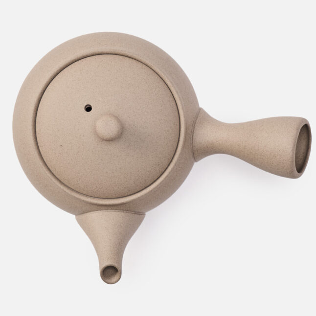 A beige rounded teapot for green tea with a handle on the side