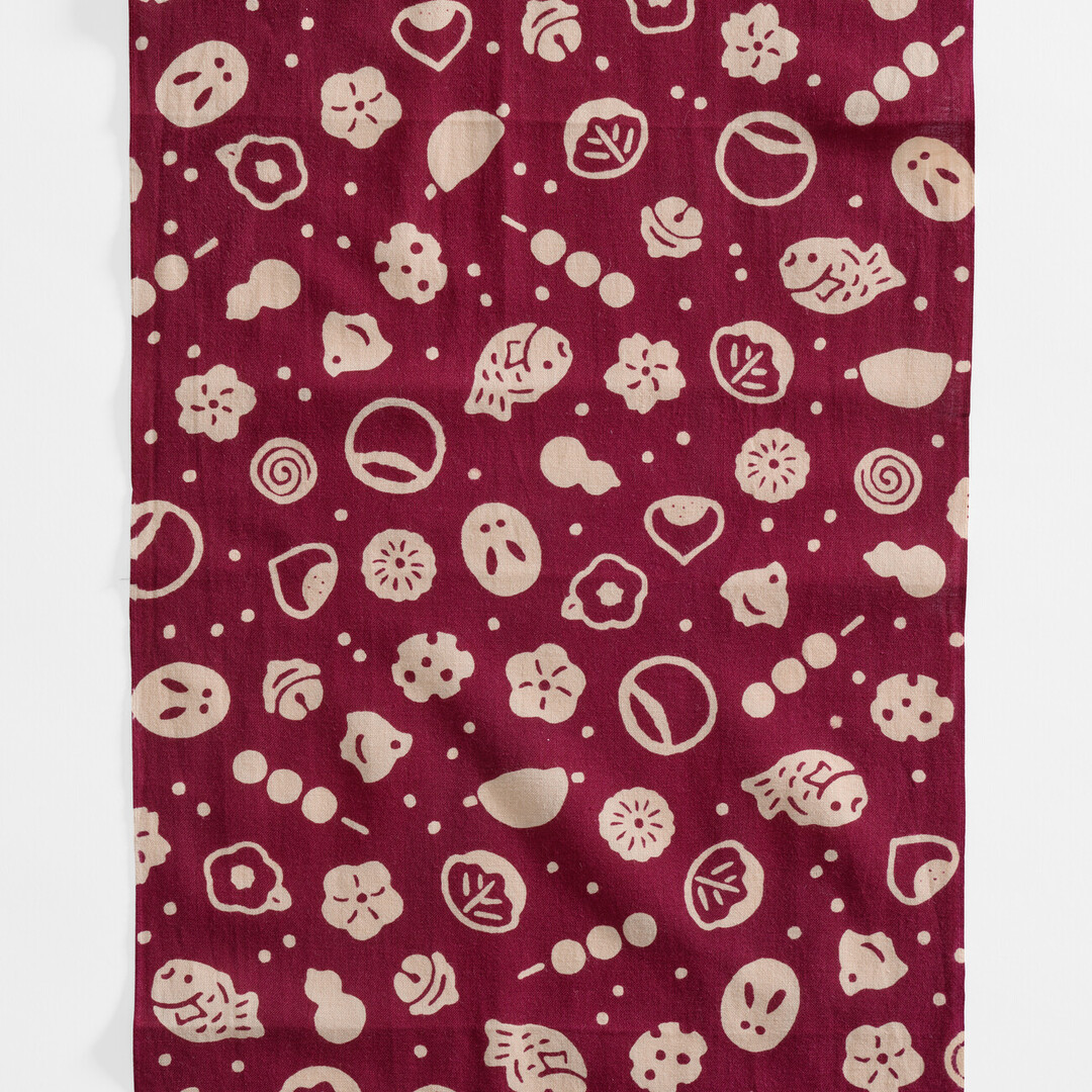 A reddish brown tenugui with beige pictograms of Japanese confectionery