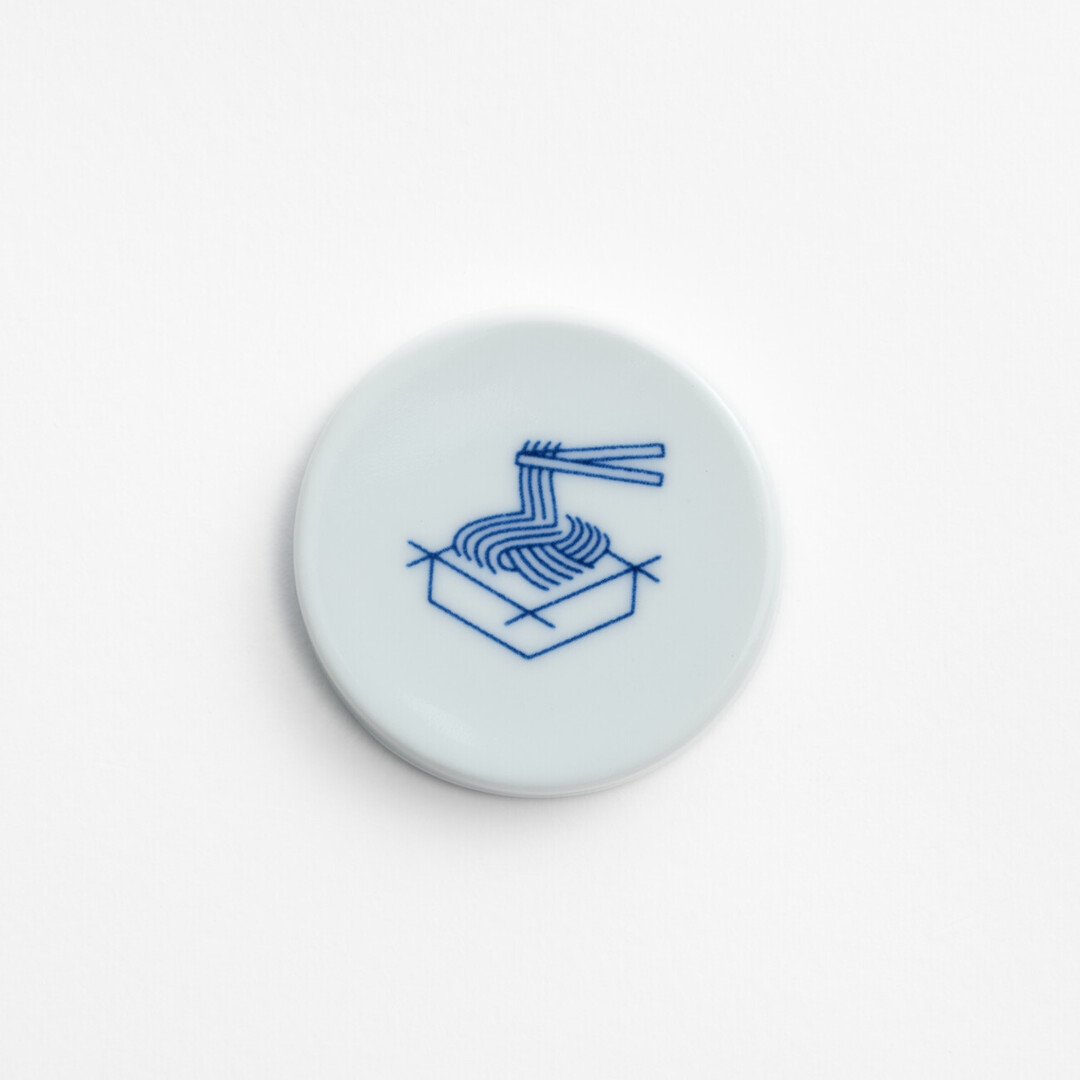 The Arita porcelain magnet with a blue line drawing of soba being picked up with chopsticks