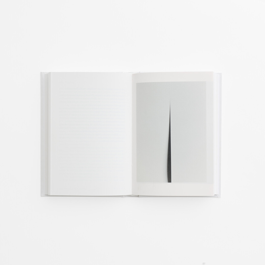 An open spread of the book 100 Whites by Hara Kenya with white pages and black and white photography