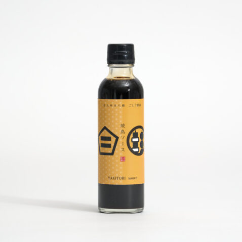 Yakitori sauce in a thin tall bottle with a beige label with black writing