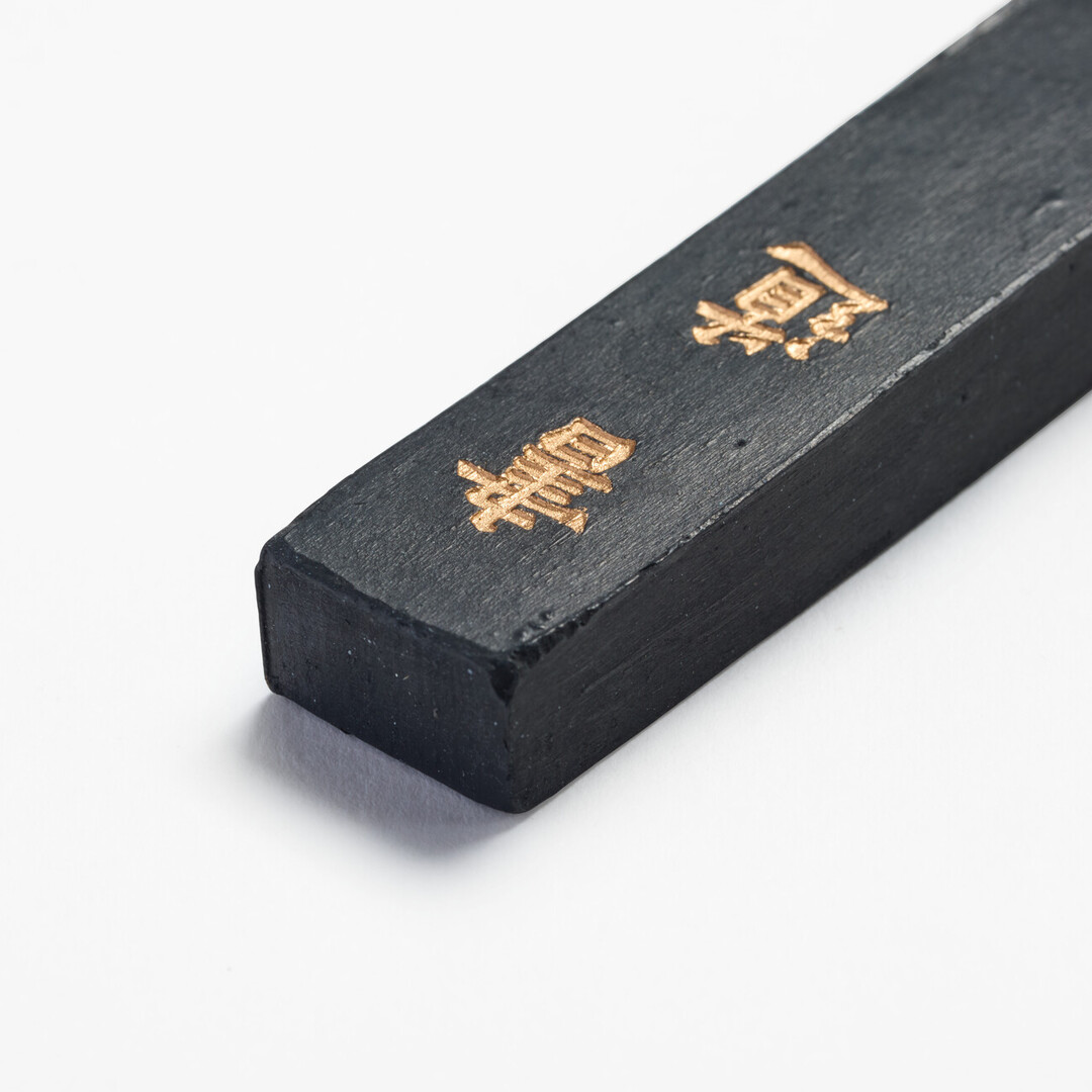 Black ink stick with gold Chinese characters of shodō from Japan House London