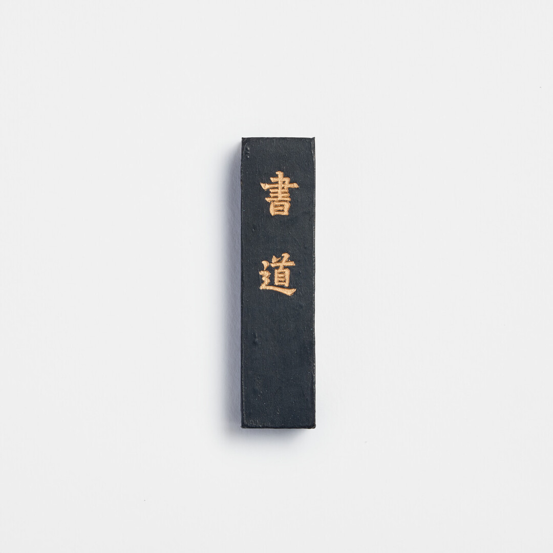 Black ink stick with gold Chinese characters of shodō from Japan House London