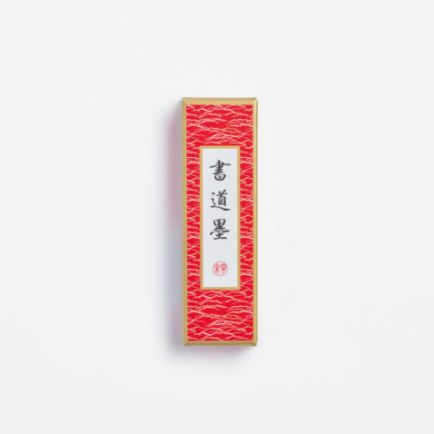 Black ink stick for shodō in a red box with the Japanese characters shodō ink from Japan House London