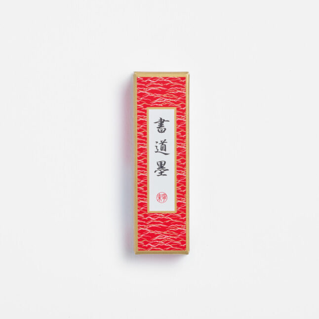 Black ink stick for shodō in a red box with the Japanese characters shodō ink from Japan House London