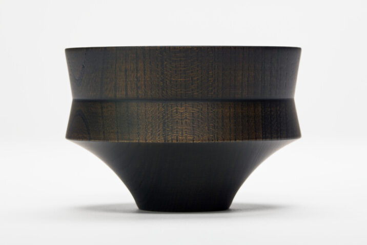 A black hand turned wooden bowl shaped like a mallet