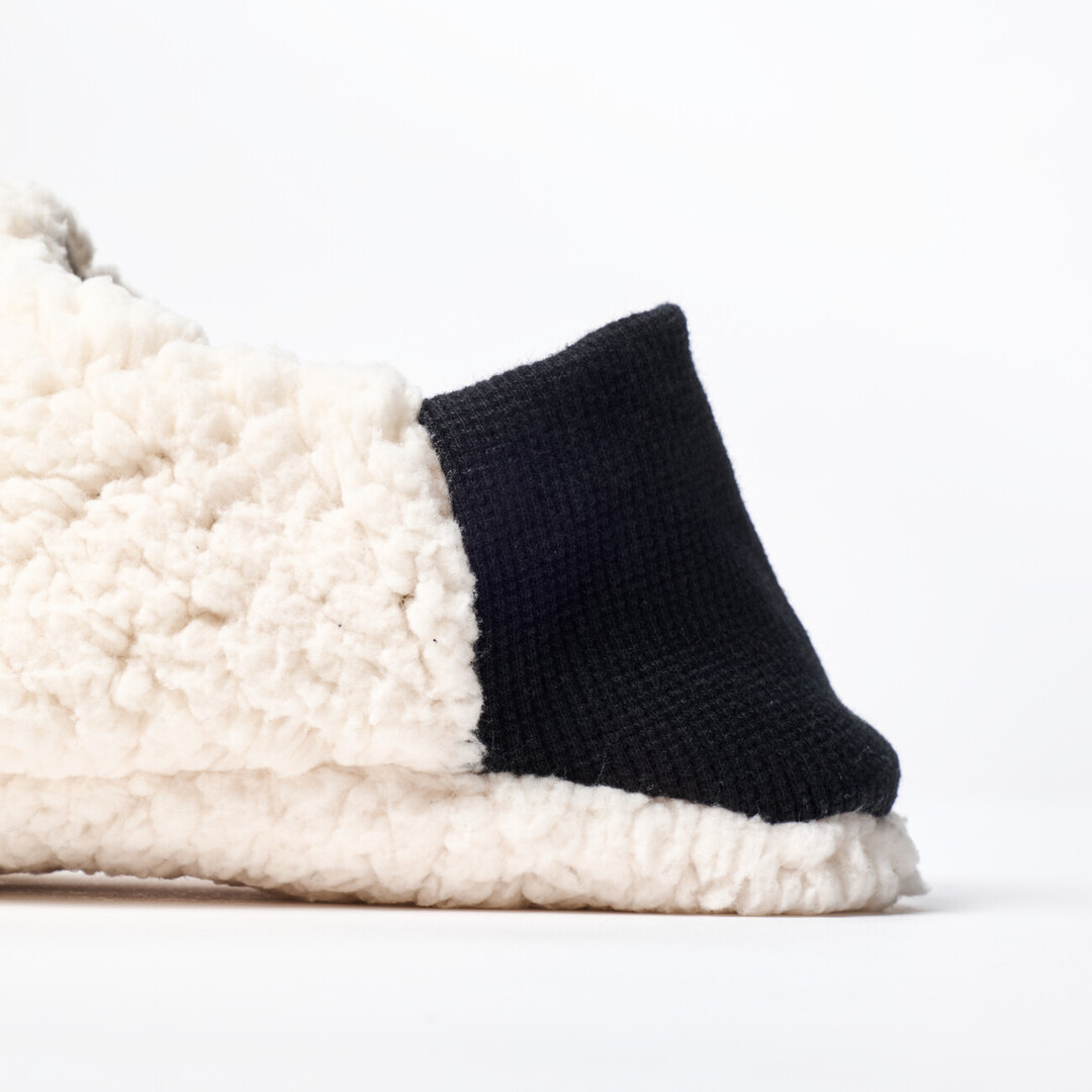A reversible slipper with a white sheep boa fabric with a black ribbed heel from Japan House London.
