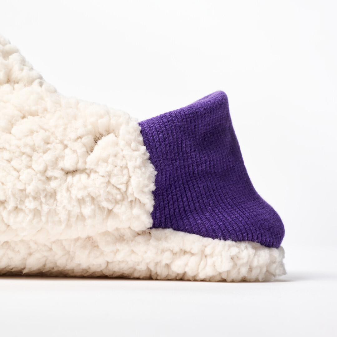 A reversible slipper with a white sheep boa fabric with a purple ribbed heel from Japan House London.