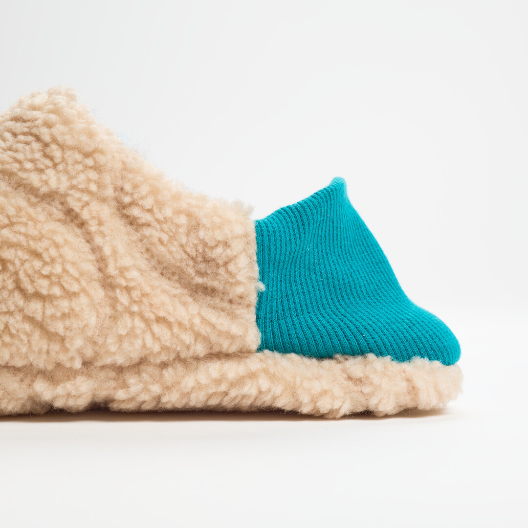 One reversible slipper made with a beige shaggy fabric a turquoise ribbed heel from Japan House London.