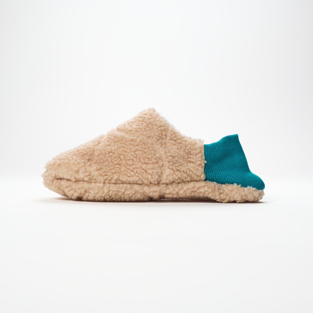 One reversible slipper made with a beige shaggy fabric a turquoise ribbed heel from Japan House London.