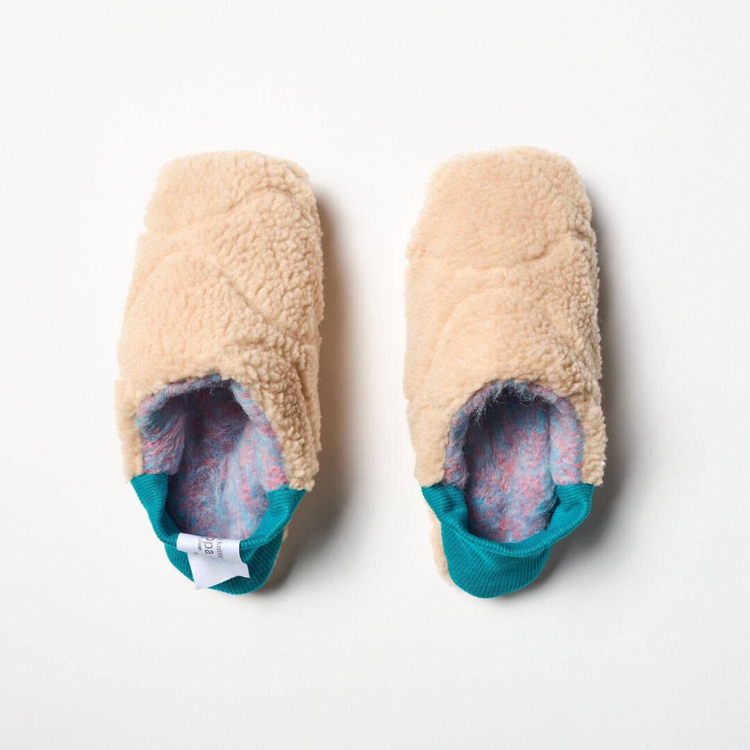 A pair of reversible slippers with a felted purple and blue blended fabric and a beige shaggy fabric on the other side with a turquoise ribbed heel from Japan House London.