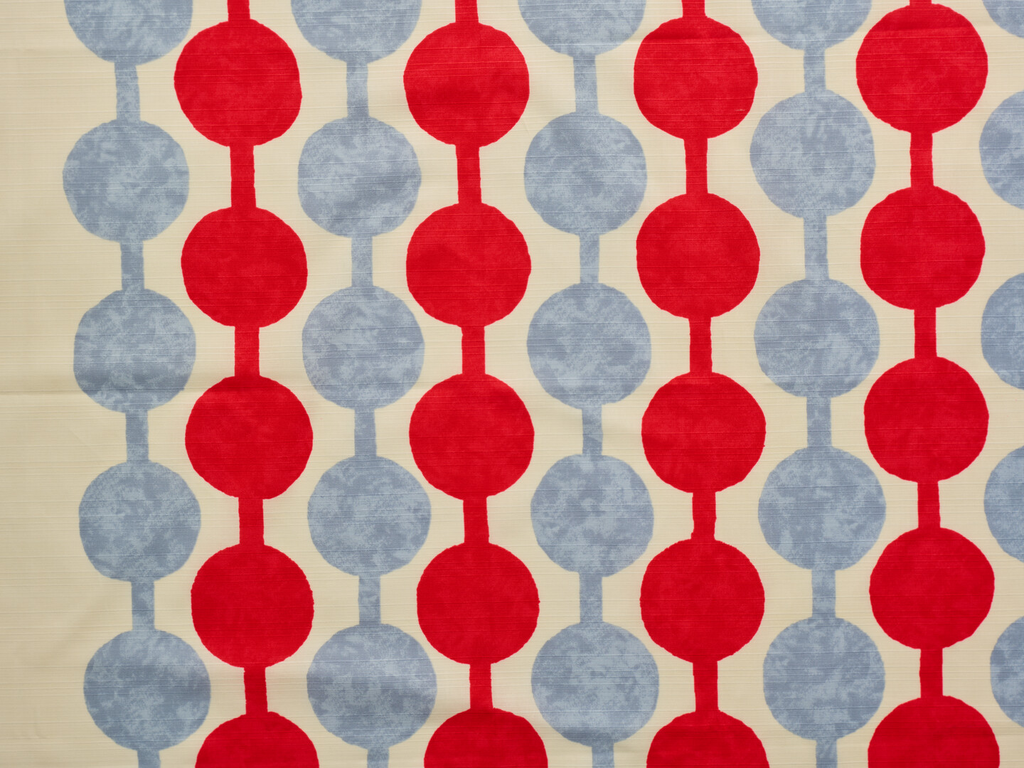 A furoshiki with red and grey pattern of spots and stripes on a cream background from Japan House London.