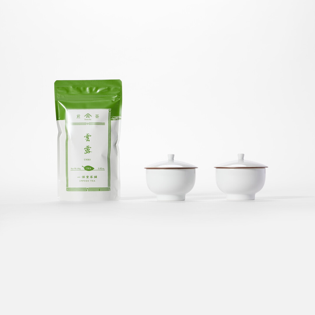 A bag of Unro green tea with two white tea cups from Japan House London.