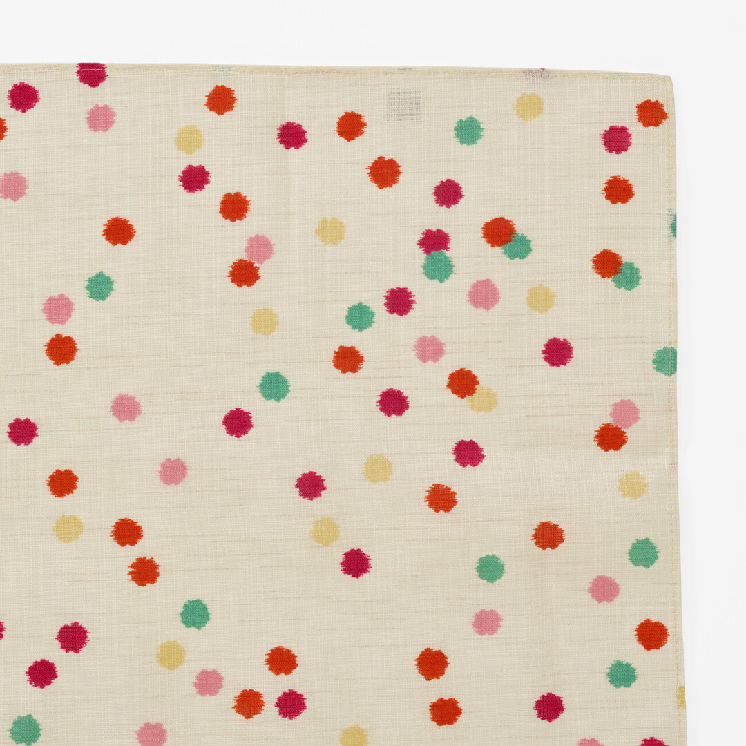 A corner of the Furoshiki Kompeito which has a cream background with multi colour small dots from Japan House London.