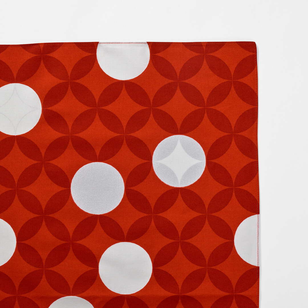A corner of the Furoshiki Seven Treasures with a red background and white circles from Japan House London.
