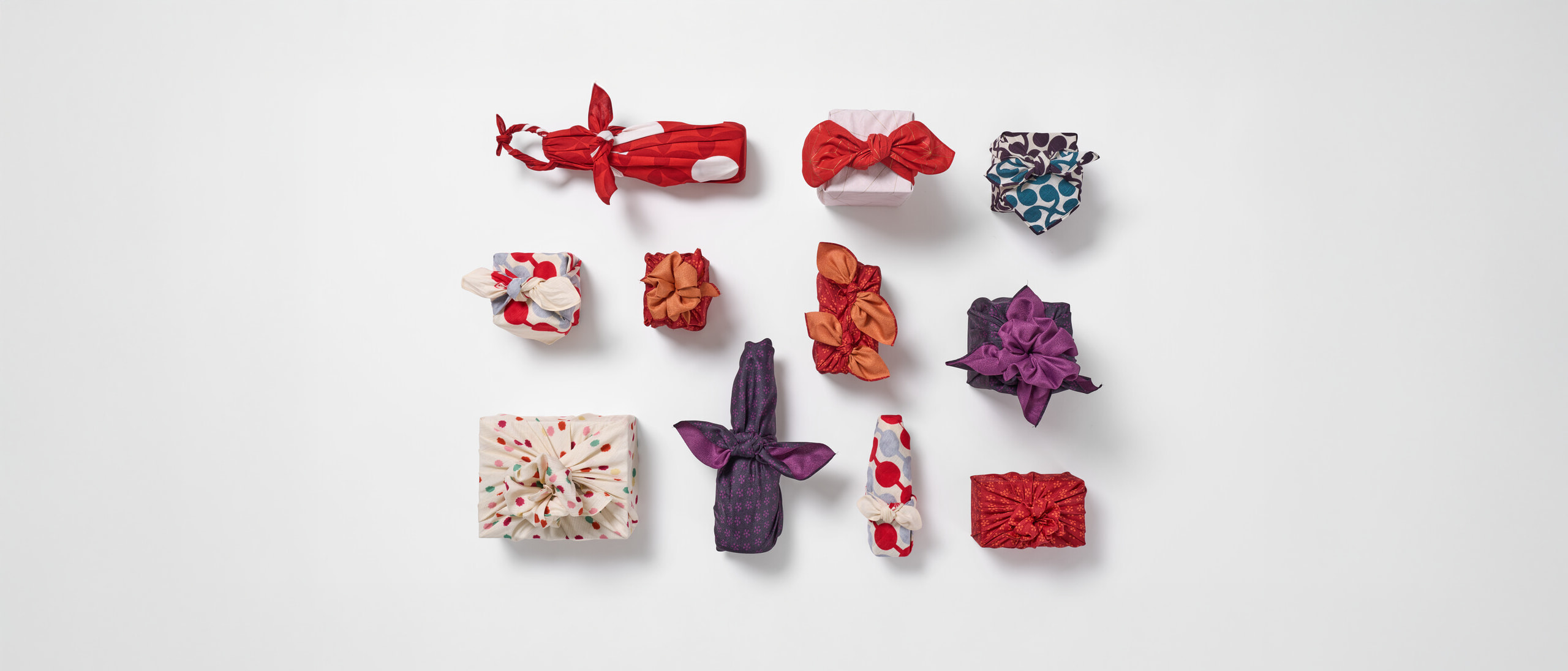 Eleven gifts wrapped in patterned furoshiki in three rows and a rectangular formation by Japan House London.