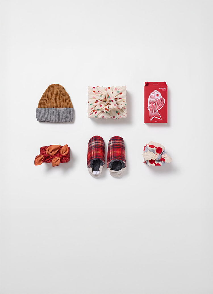 Two rows of presents, three wrapped in furoshiki, the other three are 8 way cap, sea bream soap and merippa Japanese slippers from Japan House London.