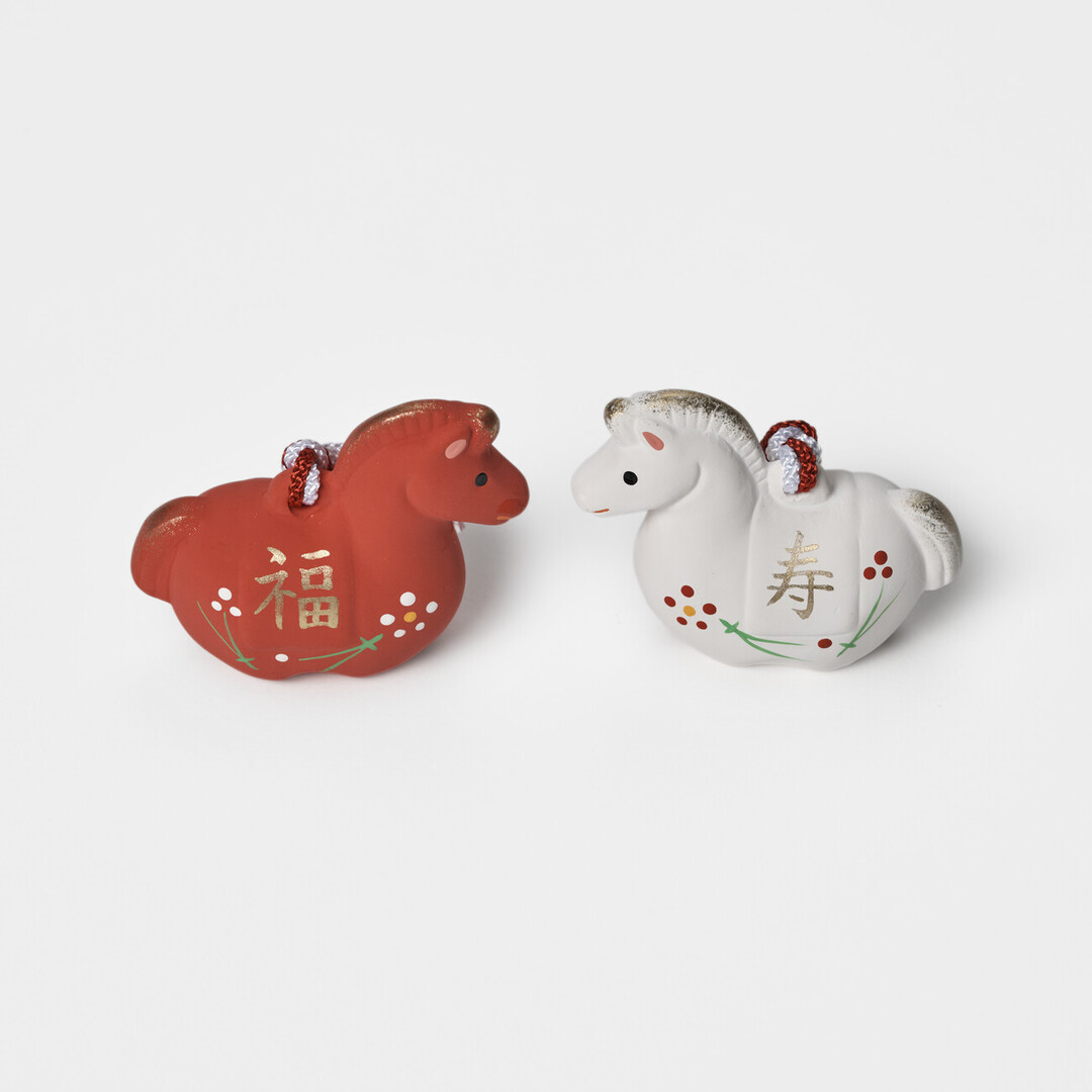 A pair of earthenware bell in red and white in the shape of a horse by Kyugetsu from Japan House London.