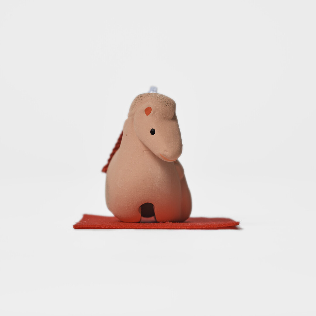 An earthenware bell in the shape of a mare and foal on a red mat by Kyugetsu from Japan House London.