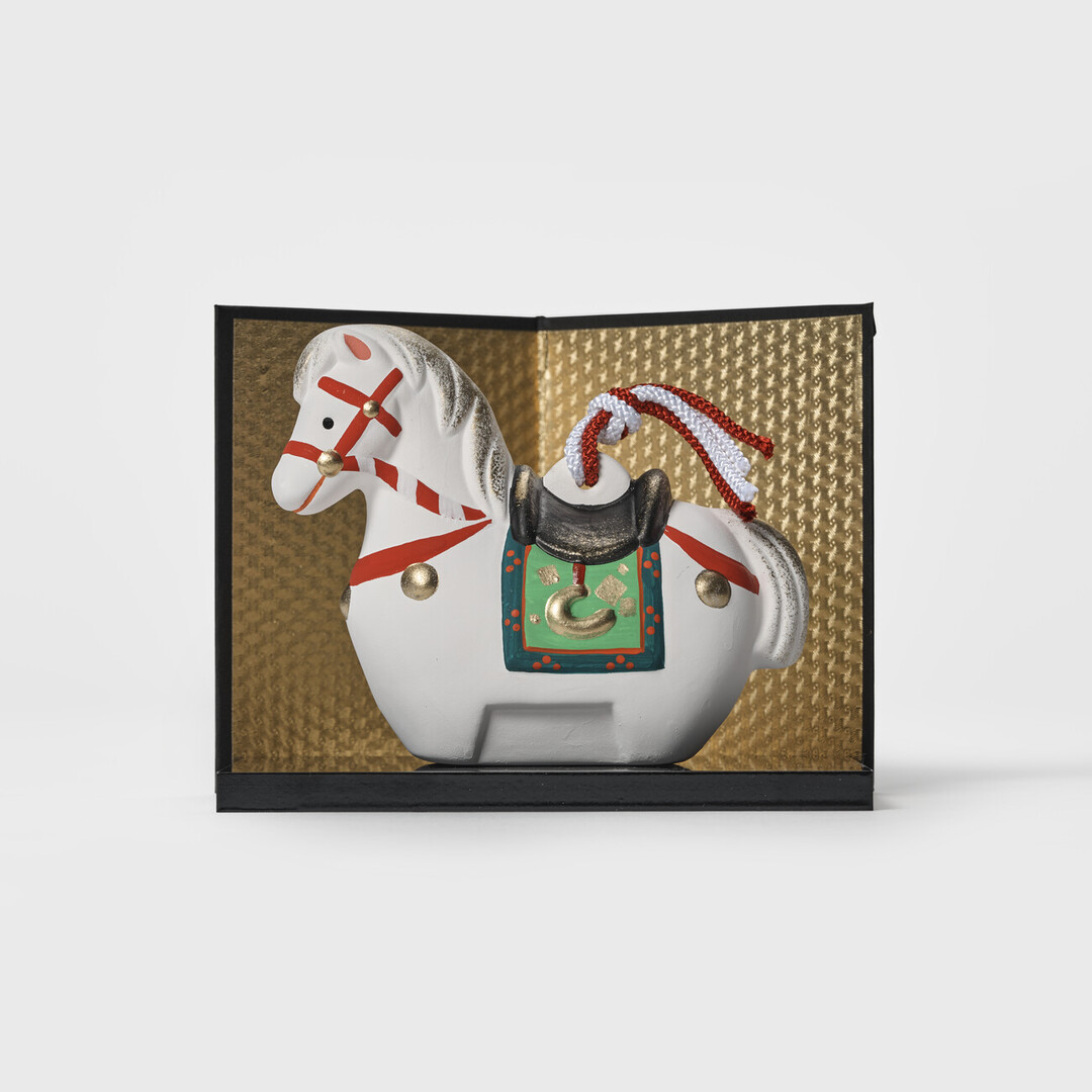 An earthenware horse bell on a black platform and gold screen by Kyugetsu from Japan House London.