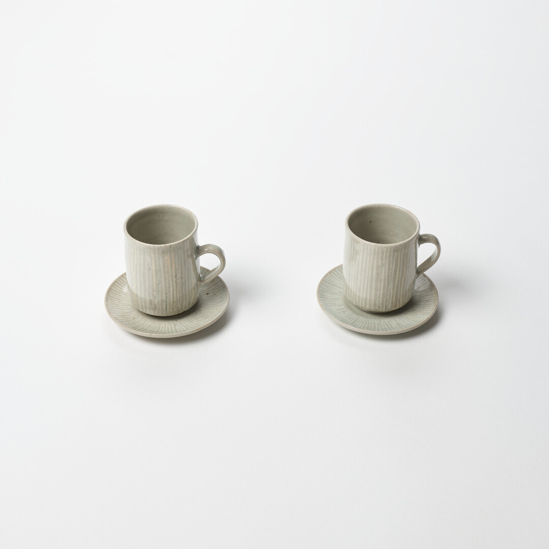 Two small ceramic cups and saucers with white stripes by Hidaka Shinji from Japan House London.