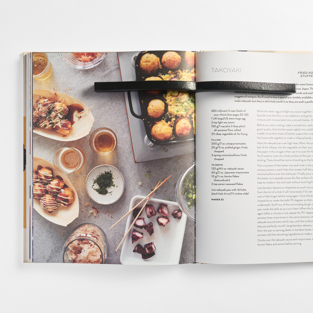 A black cast iron metal paperweight in the shape of a book on a cooking book from Japan House London.