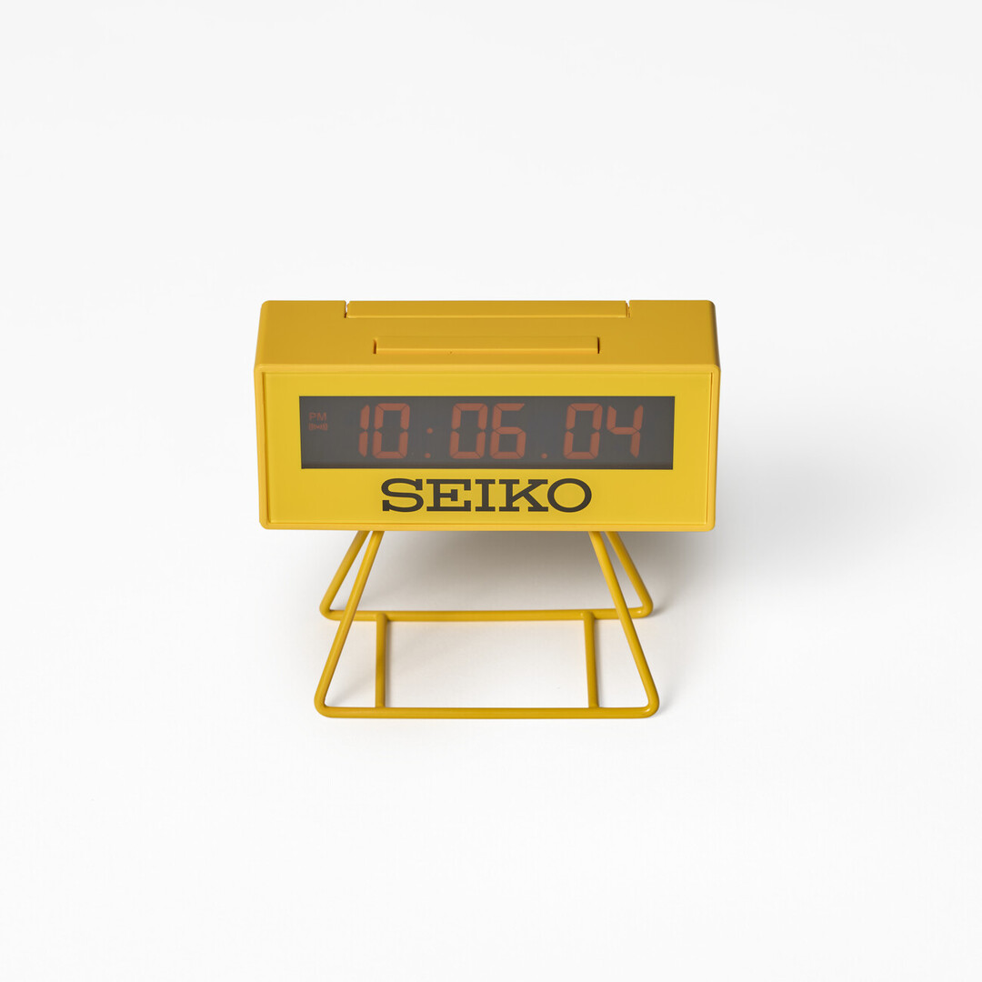 A small yellow Seiko Sports Multi-Function Digital Mantel Clock with legs from Japan House London.