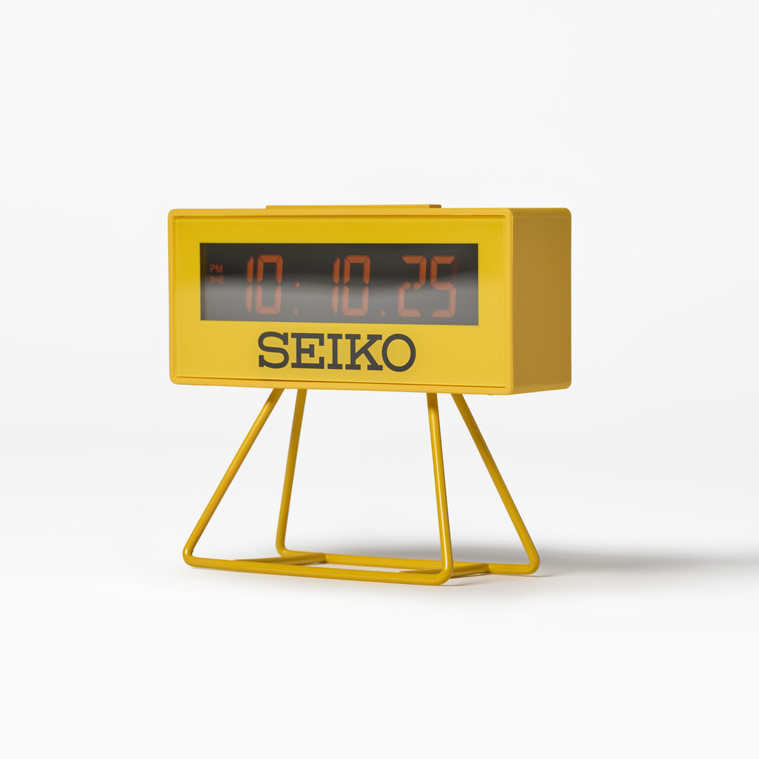 A small yellow Seiko Sports Multi-Function Digital Mantel Clock with legs from Japan House London.