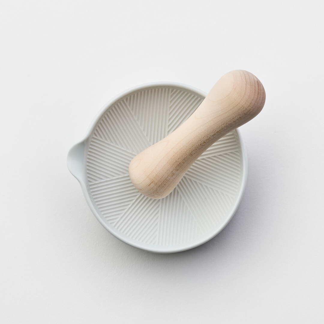 A white porcelain mortar and wooden pestle by Kihara from Japan House London.