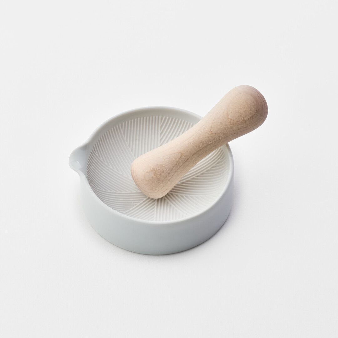A white porcelain mortar and wooden pestle by Kihara from Japan House London.