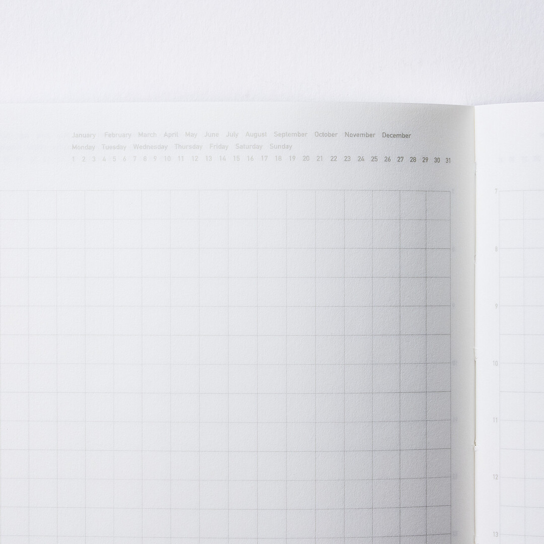 The days of the month, the months of the year and the numbers of the day written on top of a gridded area of the page of STALOGY 1/2 Year Notebook B6/black from Japan House London.