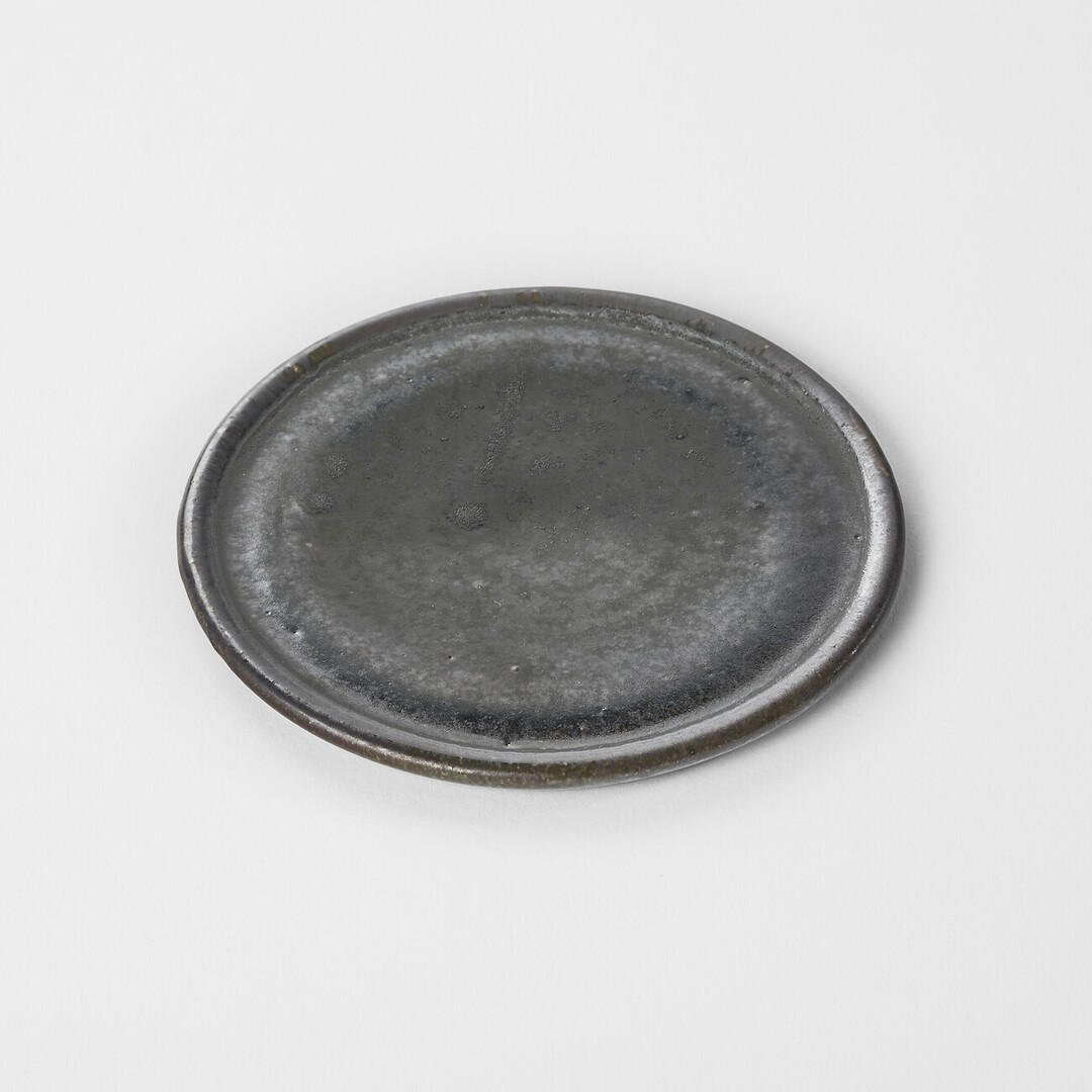 A small circular ceramic plate with black glaze by Shimomura Atsushi from Japan House London.