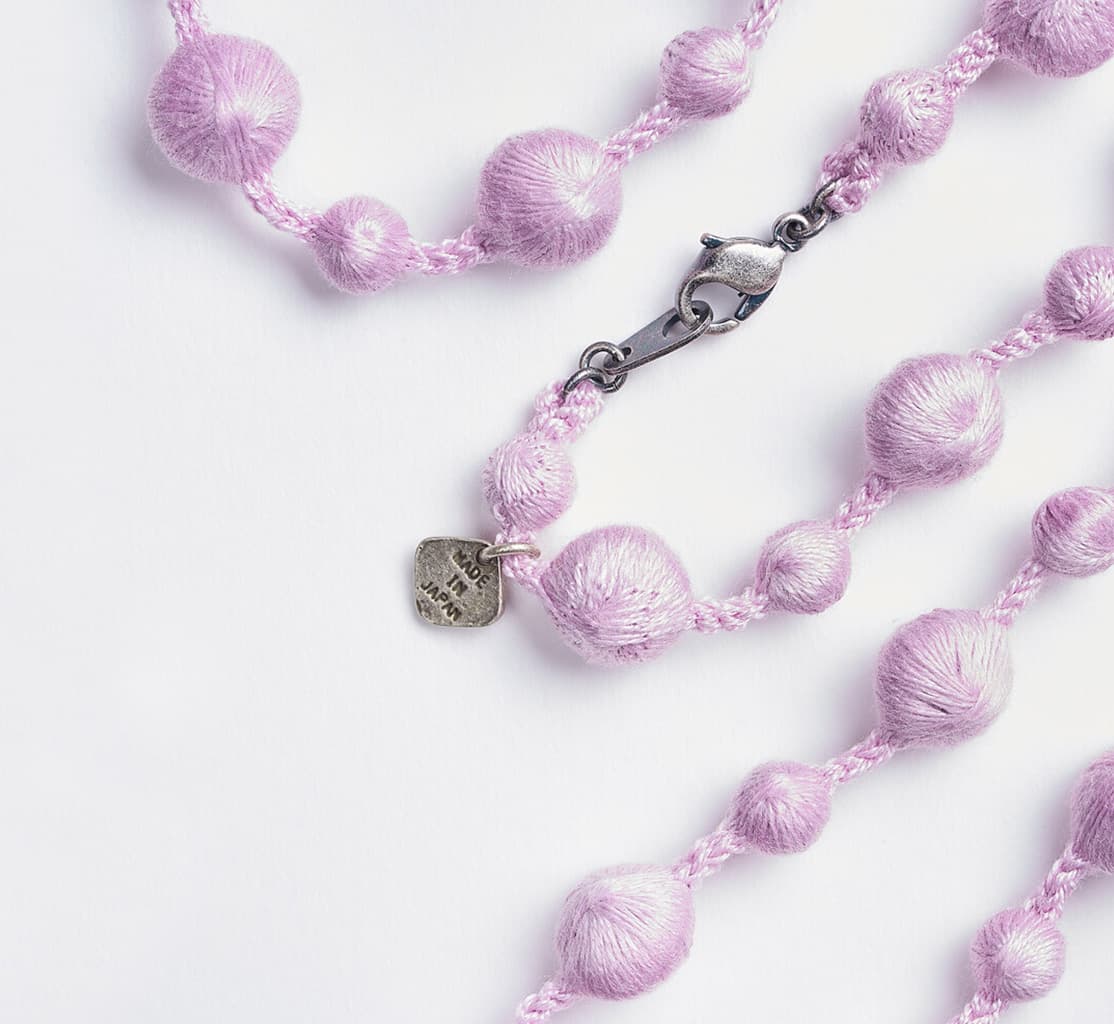A lilac necklace created from embroidered spheres with metal clasp by Triple O from Japan House London.
