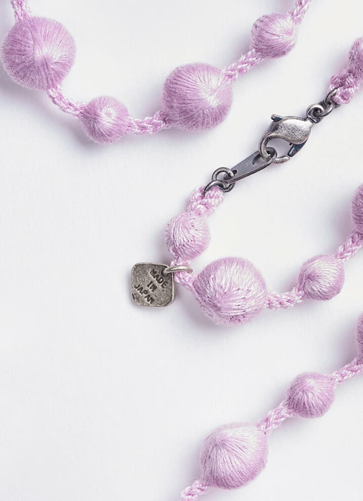 A lilac necklace created from embroidered spheres with metal clasp by Triple O from Japan House London.