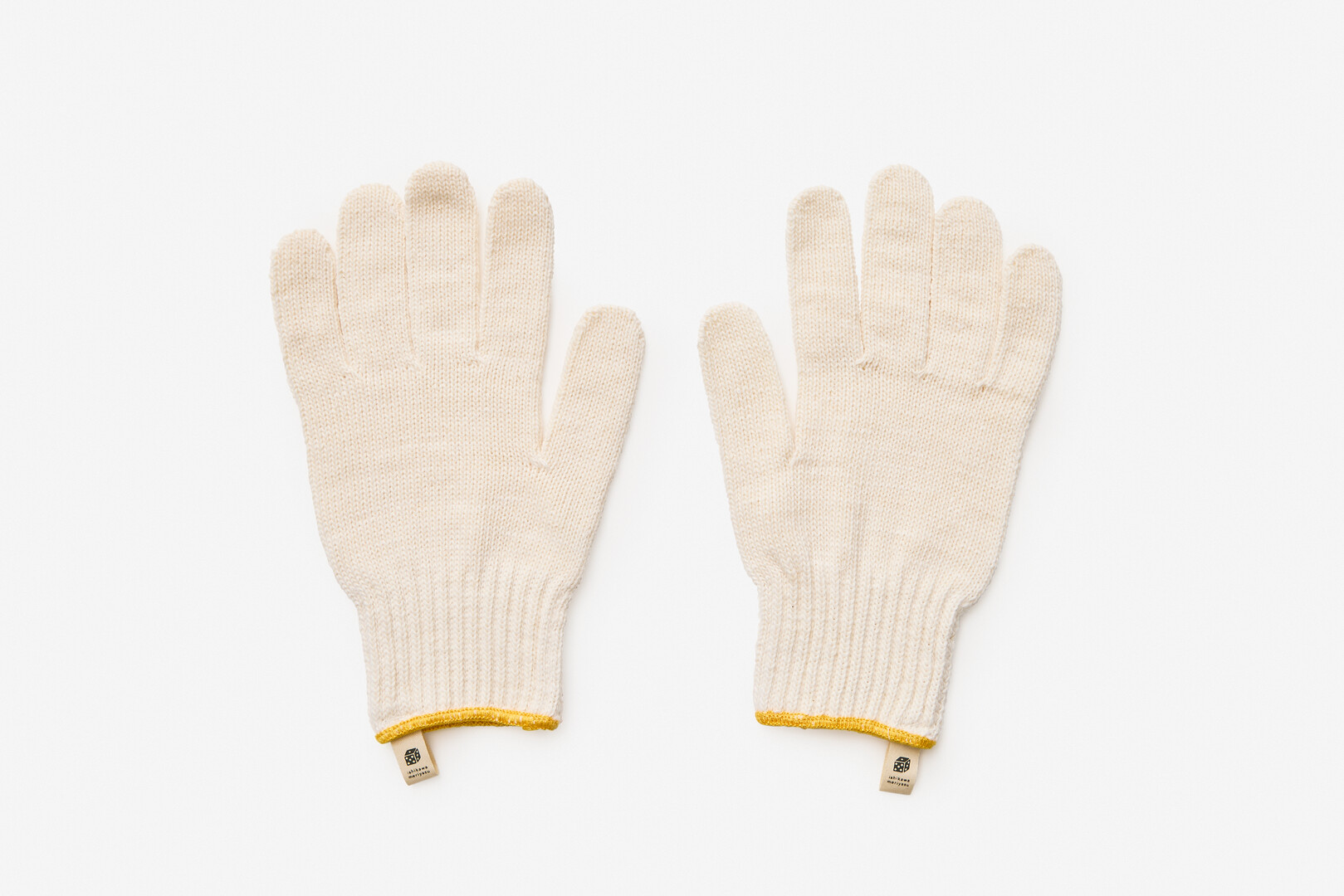 White work gloves with a band of yellow around the wrist from Japan House London.