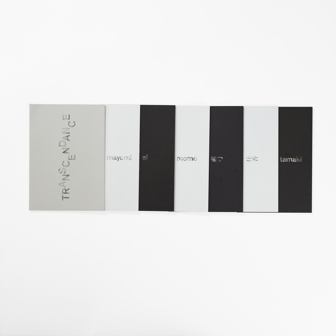 White box with the title 'Transcendance' with six different artist pamphlets in black and white from Japan House London.