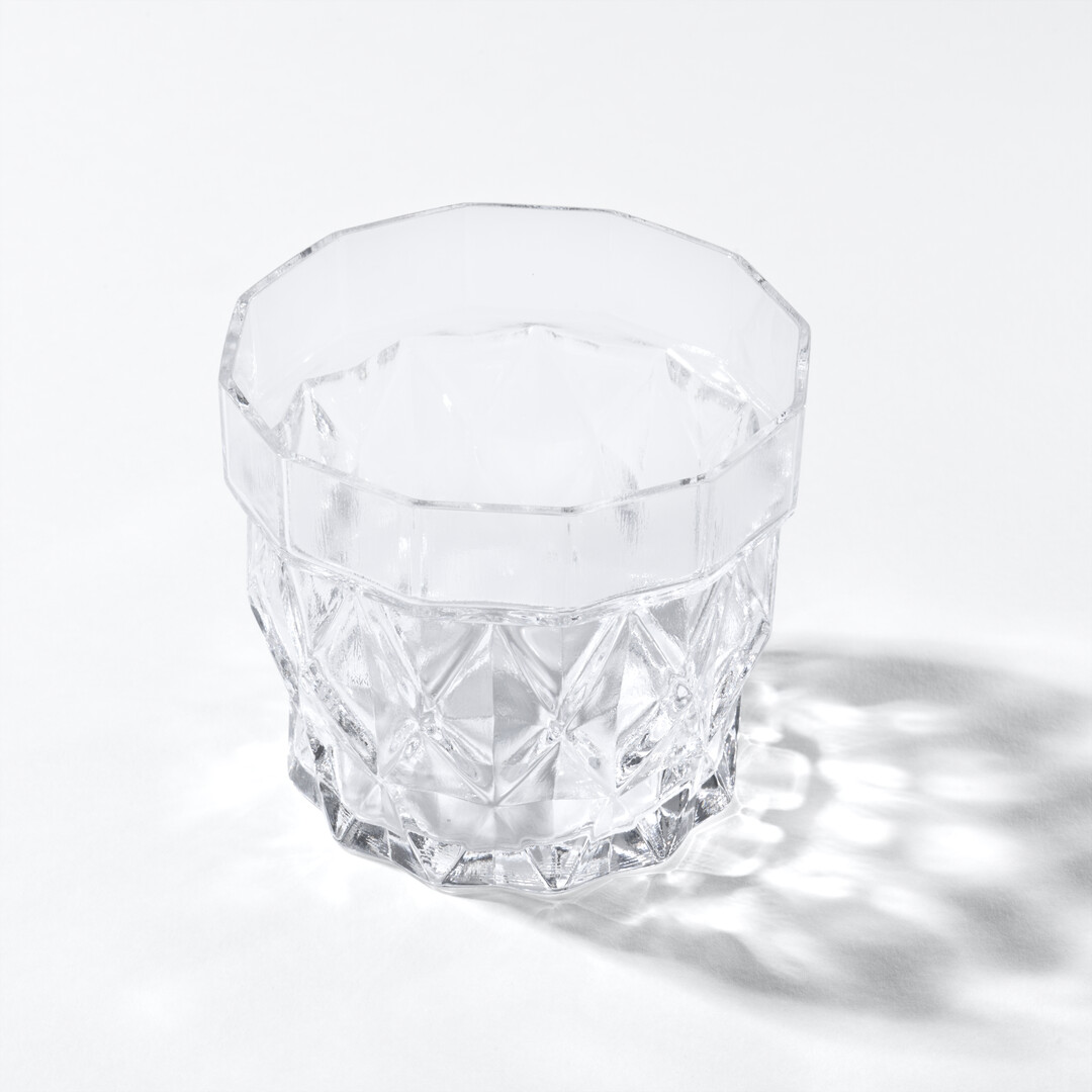 Whisky Glass Stium in glass with a patterned wall from Japan House London.