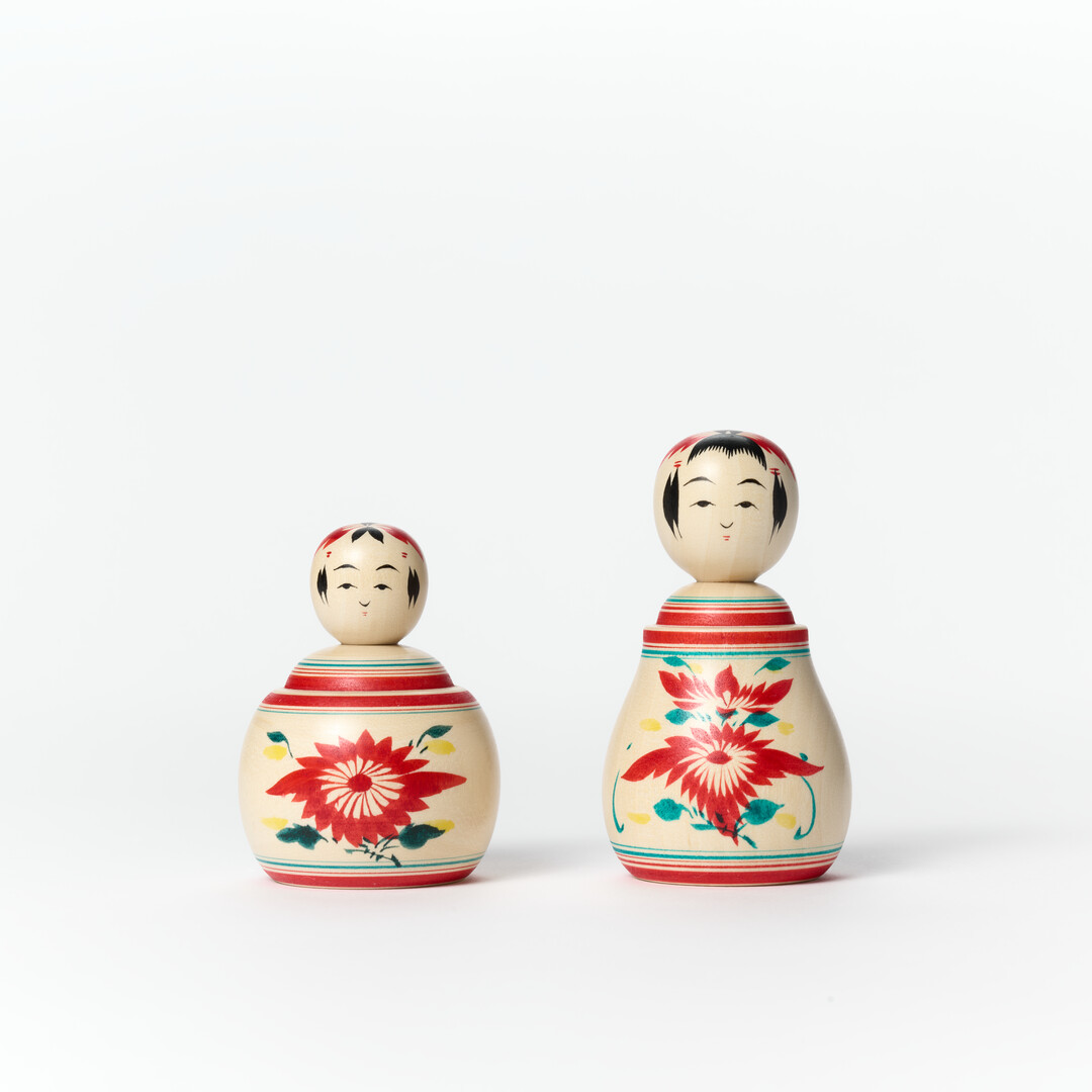Two kokeshi dolls, on the right Naruko Wooden Kokeshi Doll Nemariko in Small and on the left Naruko Wooden Kokeshi Doll - Ejiko - Small