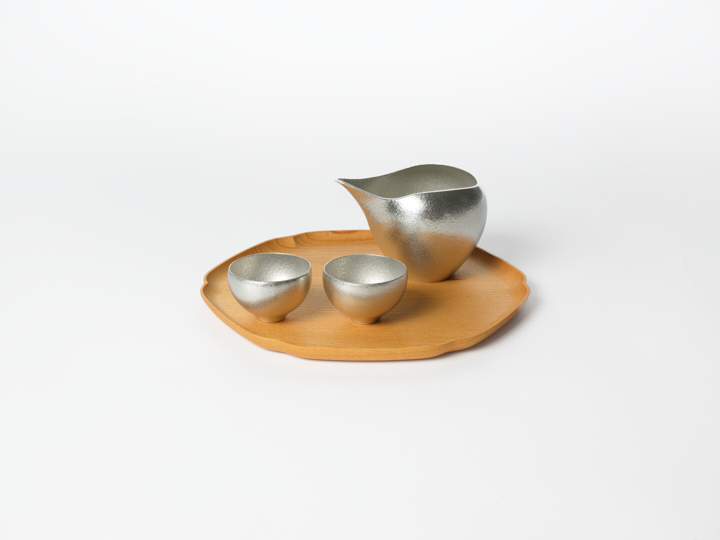 Tin sake pourer and sake cups on a wooden tray from Japan House London