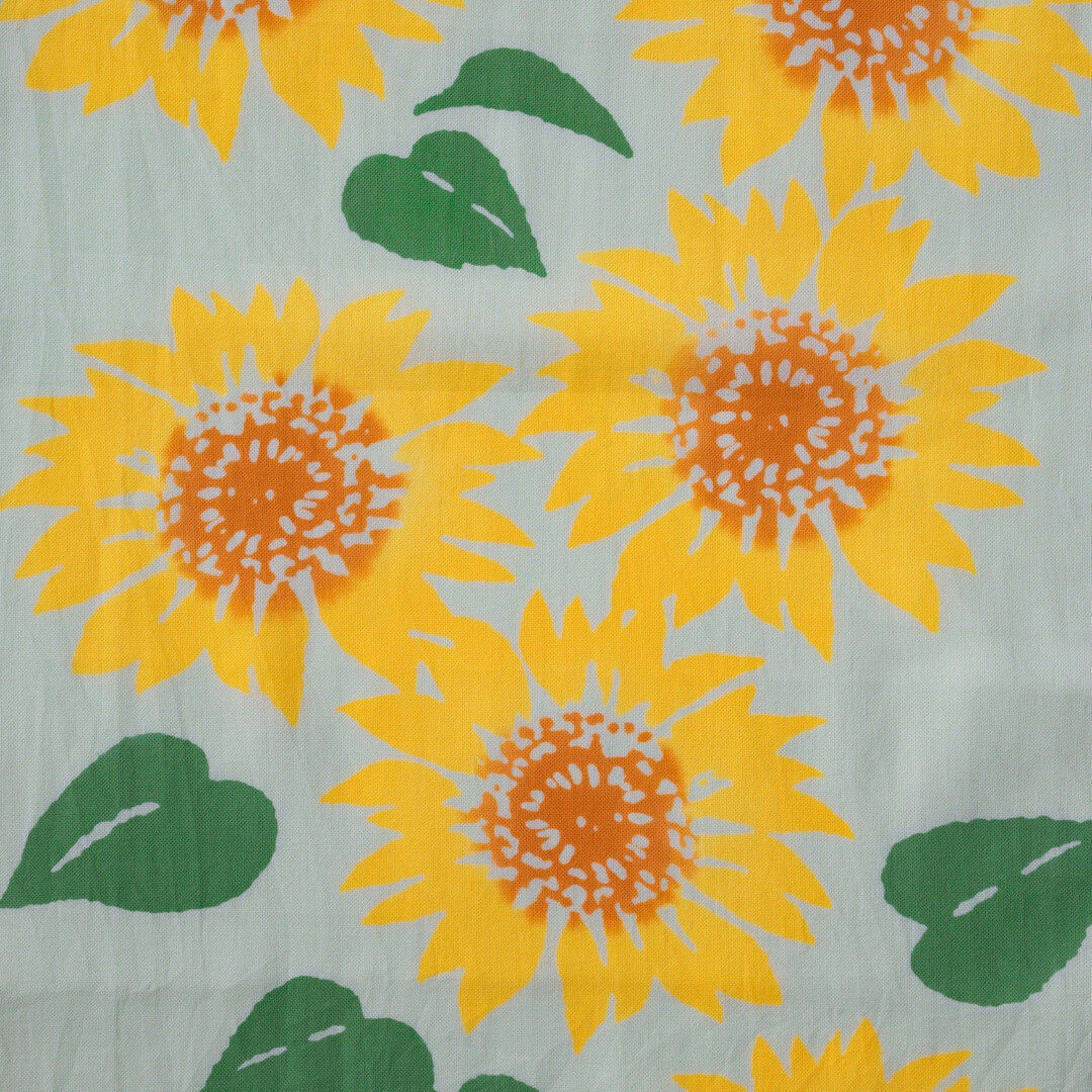 A tenugui with brightly coloured Sunflower on a light blue background by Kamawanu from Japan House London
