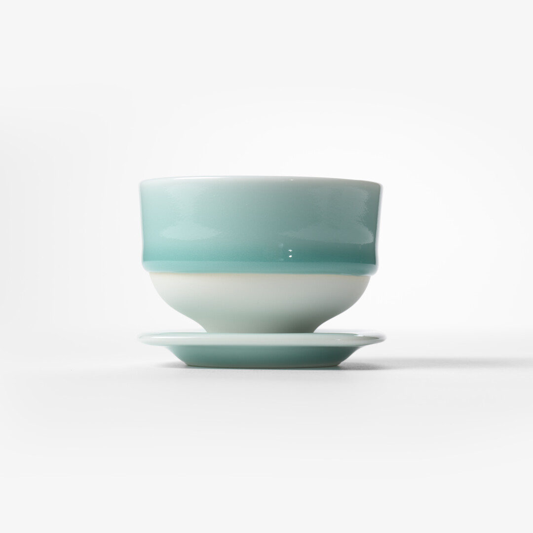 Nabeshima Celadon tea cup in a light turquoise on a small plate used as a saucer from Japan House London.
