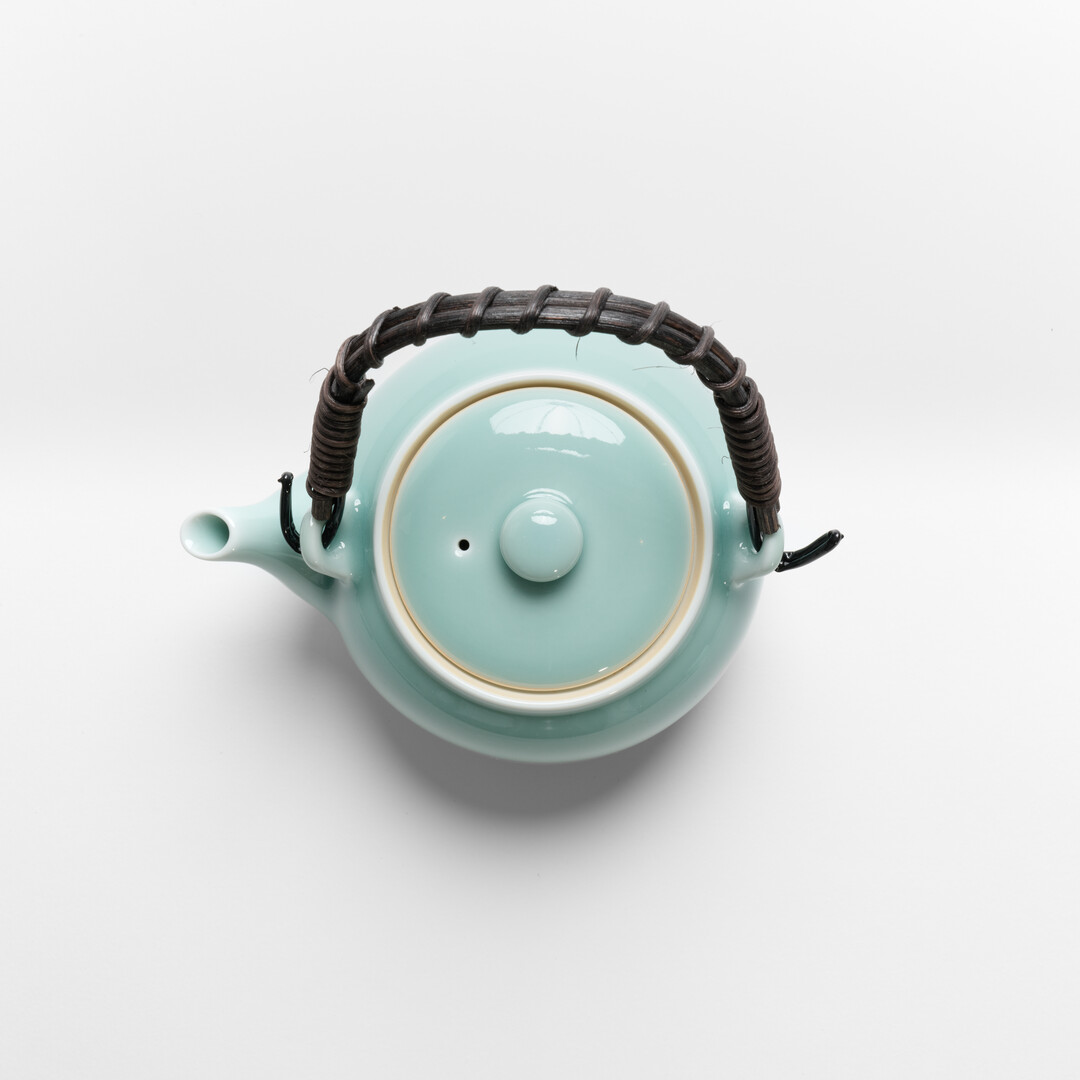 Nabeshima Celadon teapot in turquoise with natural fibre woven handle from Japan House London.
