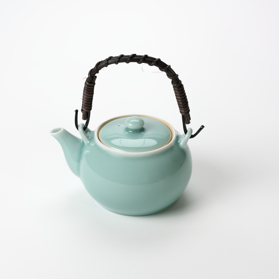 Nabeshima Celadon teapot in turquoise with natural fibre woven handle from Japan House London.