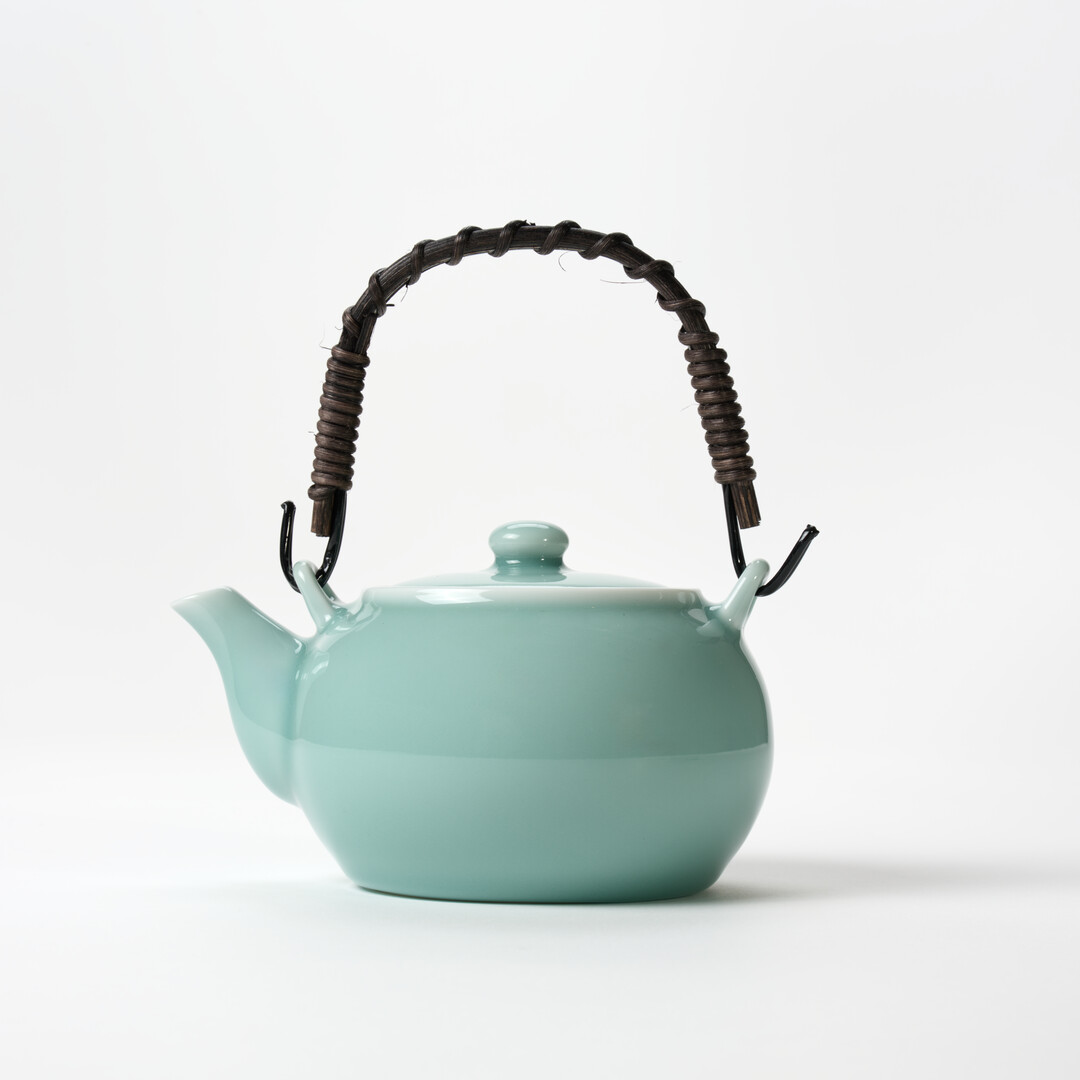 Nabeshima Celadon teapot in turquoise with natural fibre woven handle from Japan House London.